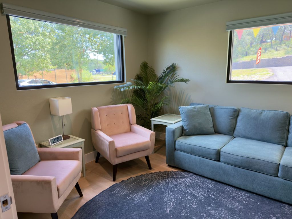 Calm therapy room with a blue sofa and pink armchairs at Adoration